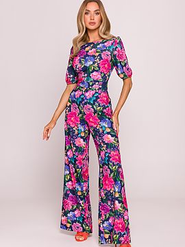 Overal Moe  Štýlový overal vyrobený z jemnej látky s matným povrchom, zdobený viacfarebným kvetinovým potlačou. Kombinácia priliehajúcej hor